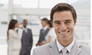 Portrait of happy young businessman with colleagues in the background